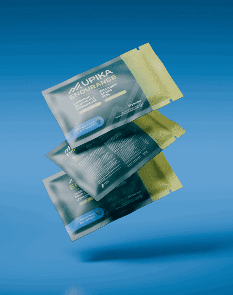 Trois sachets flottants du complément Upika Endurance sont représentés sur un fond bleu. L'emballage est vert et jaune, avec un texte blanc et des détails sur le produit visibles au recto et au verso.